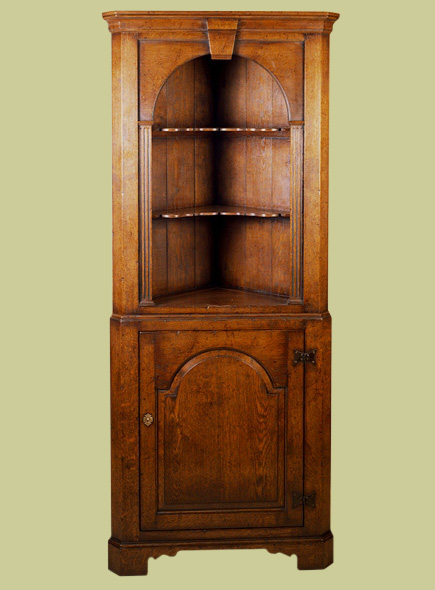 Oak corner cupboard with attractive open display area featuring fluted stiles and an arched top with period style 