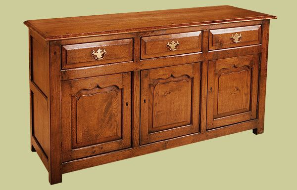 Oak enclosed low dresser with three attractive ogee shaped doors and three fielded front drawers.