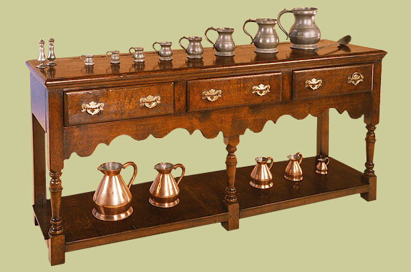 Oak 3 drawer low potboard dresser base, with central baluster turned leg, shaped apron and solid brass handles.