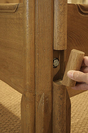 Half round oak bed moulding detached to reveal rail fixing bolt