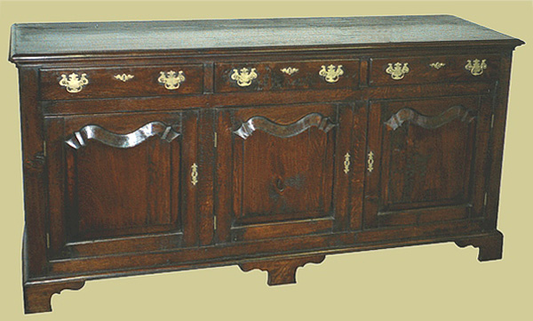 Traditional dresser, with plain and simple drawer fronts, unusual wavy shaped fielded panel cupboard doors and bracketed feet