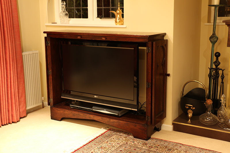 TV cabinet with medieval tracery style doors open, showing flat screen television