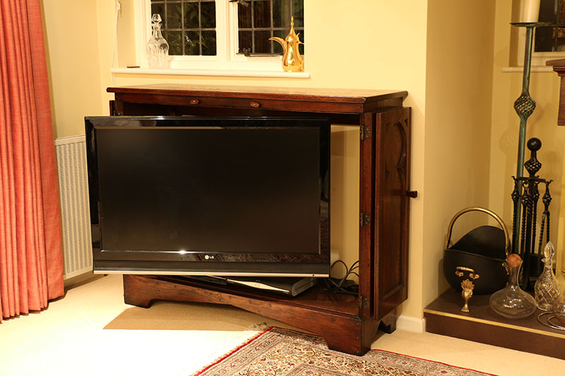 Medieval tracery style TV cabinet with television extended and swiveled for comfortable viewing