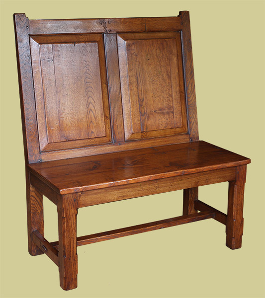 Simple raked back dining room settle with fielded oak panelled back and stop chamfered legs.