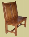 An oak dining room settle, of simple design, with raked back, fielded panels and stop chamfered legs.