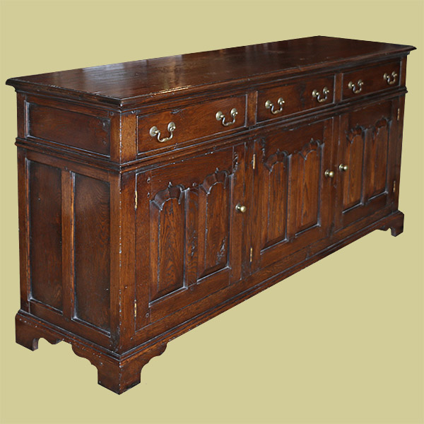 Early oak style closed dresser base, with three fielded panel doors and three drawers.