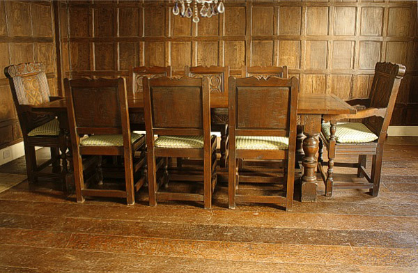 Carved oak dining table and chairs, in Tudor panelled room.