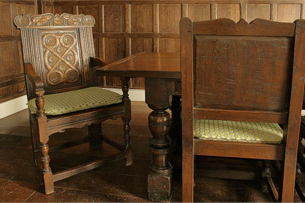 Hand carved Westmorland style oak armchair in Tudor panelled dining room.