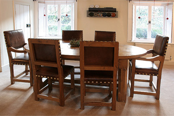 Oak oval top dining table, with stop chamfered legs, photographed with matching leather covered chairs, in our clients West Sussex home.