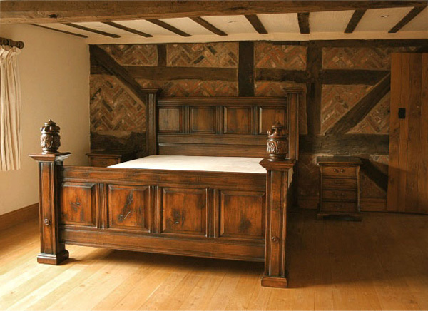 Fielded panel oak bed, with carved finials, in oak beamed house.