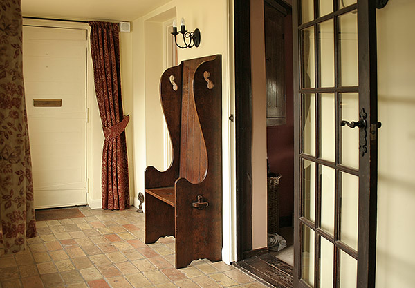 Small oak 18th/19th century period style settle, in hallway of Suffolk cottage.