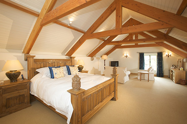 Oak linenfold carved bed and matching bedside cabinets, in master bedroom of Devon longhouse.