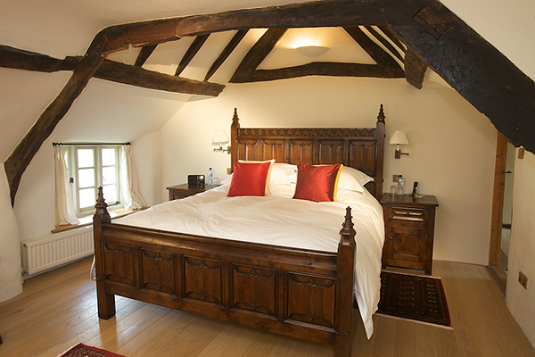 Parchemin panelled oak bed and matching bedside cabinets, in beamed bedroom of Devon longhouse.