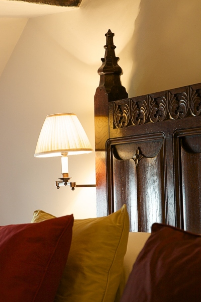 Detail photo of our bespoke 16th century style parchemin panelled bed, in the oak beamed bedroom of our clients Devon longhouse.