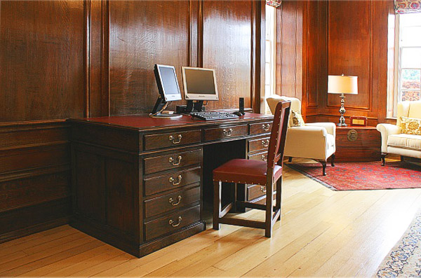 Oak pedestal desk and leather chair, in panelled room, which is part of a converted country estate.