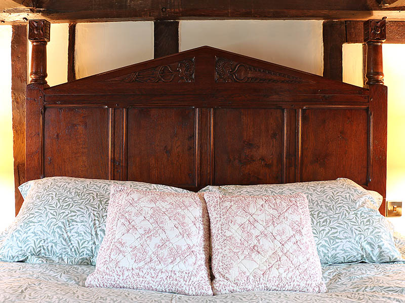Carved oak headboard of Tudor style pencil bed