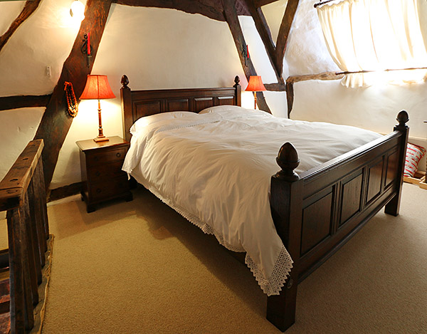 Oak panelled bed and bedside chest of drawers, in ancient cruck framed bedroom of 15th century timber framed house.