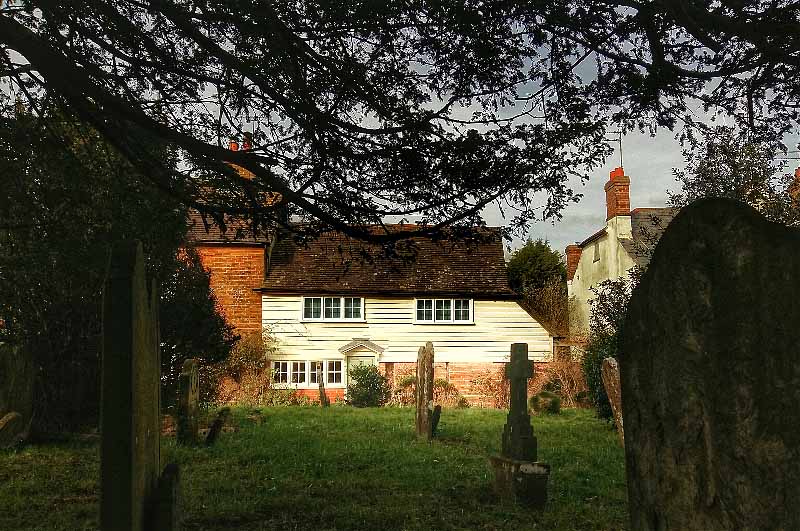 A pretty weather boarded cottage, viewed from Cowfold churchyard