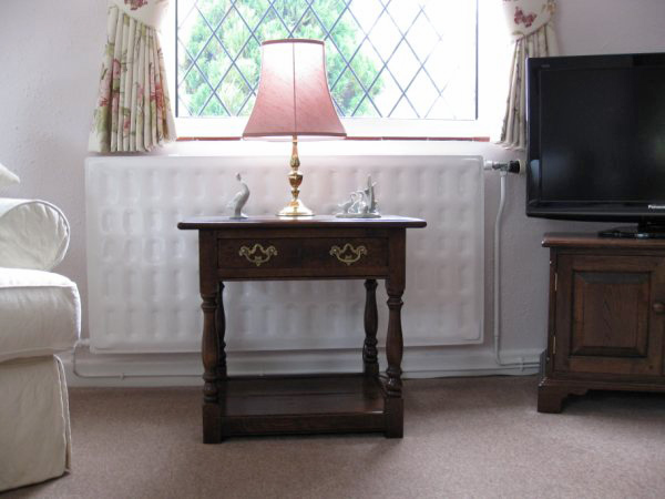Oak period style side table in modern but traditionally decorated and furnished interior.