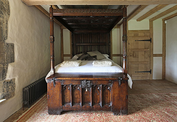 Tudor style carved oak four poster bed, in guest bedroom of 13th century Sussex country manor house.