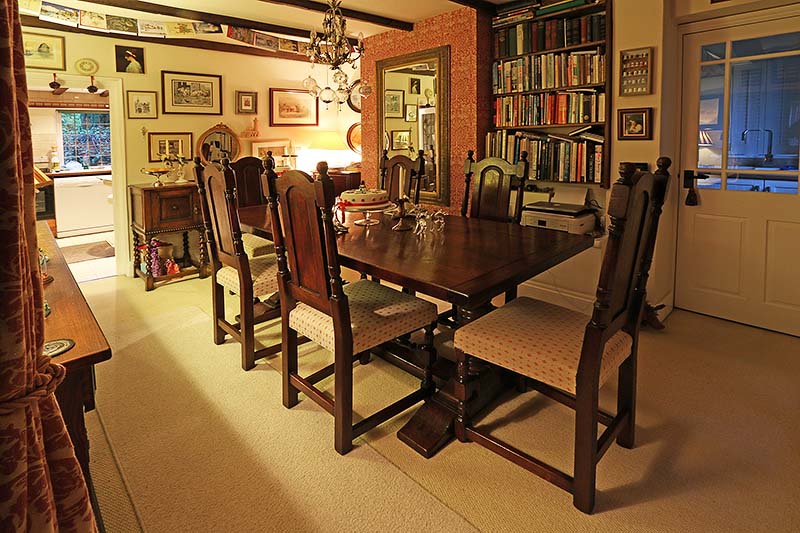 Period style pedestal table and upholstered chairs, in dining room of cottage.