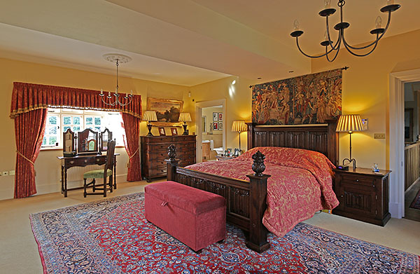 Oak linenfold carved bed, bedside cabinets, 10-drawer Jacobean style chest of drawers, dressing table, mirror and upholstered oak chair, in our clients master bedroom.