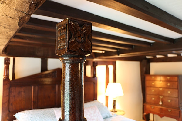 Carved detail on bed posts of Tudor style oak bed