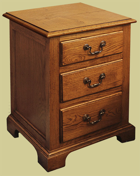 Traditional design oak bedside cabinet with 3 moulded edge drawers.