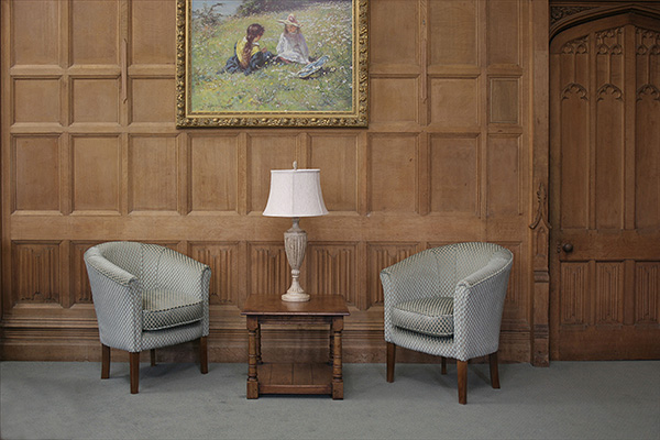 Square lamp table with doric column turned legs, in oak panelled room.